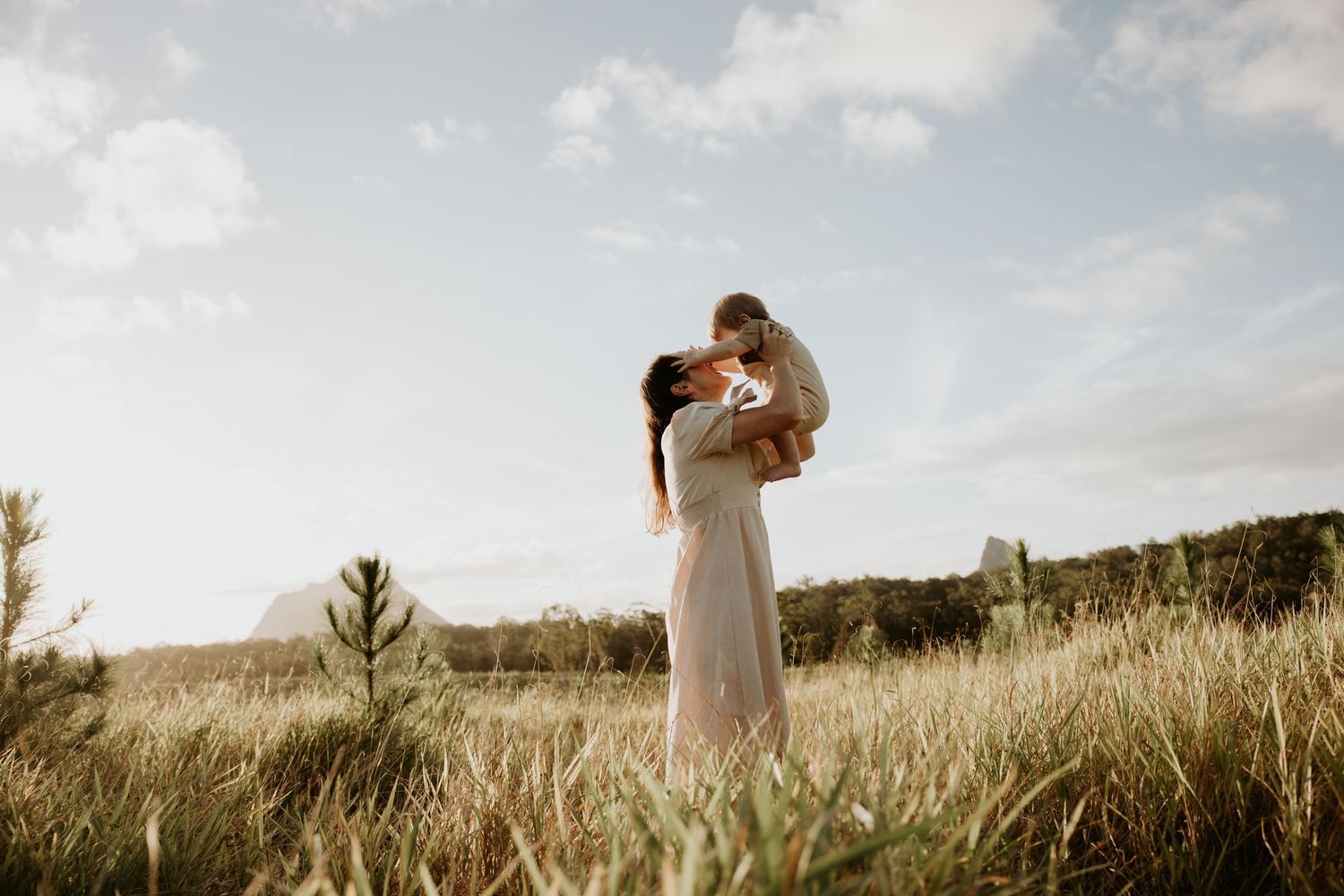 Scenic family photoshoot in an open field with dramatic sky and natural lighting.