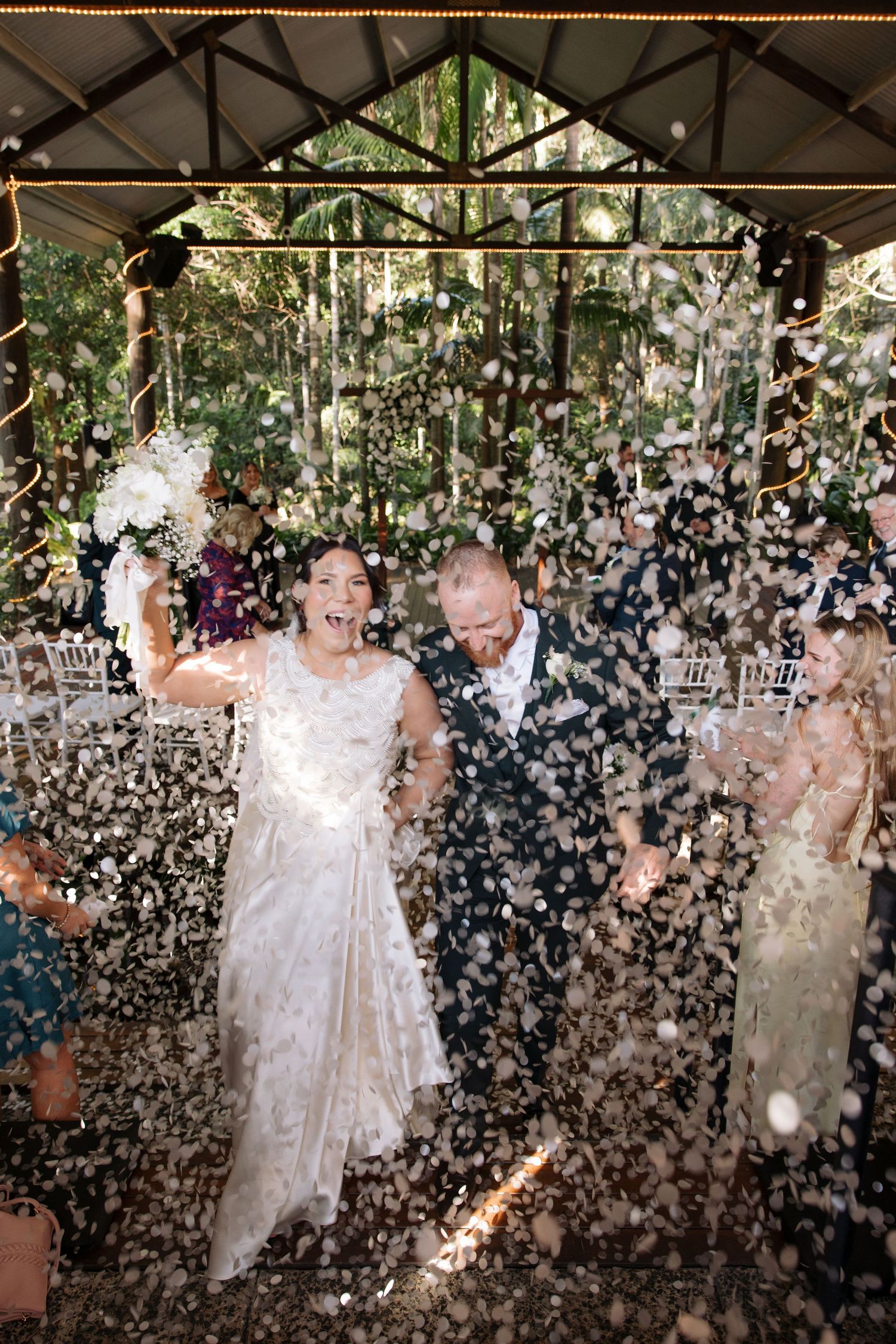 Joyful celebration moment with confetti shower during indoor wedding reception.