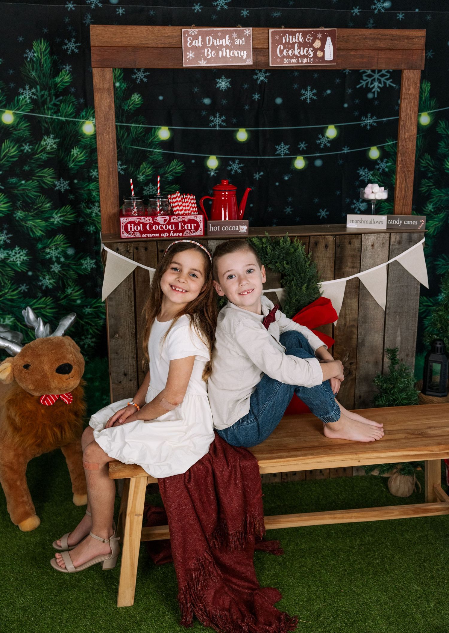 Holiday photo session with children and Christmas decorations against rustic wooden backdrop.