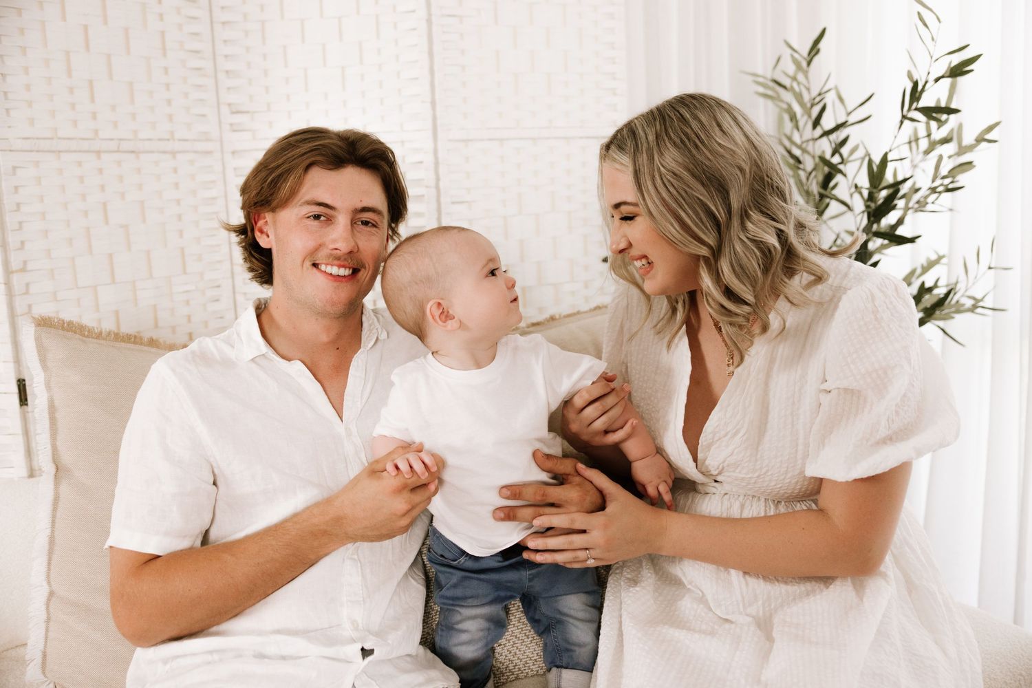 Family portrait session showing candid moments and laughter in a bright indoor setting with white decor.