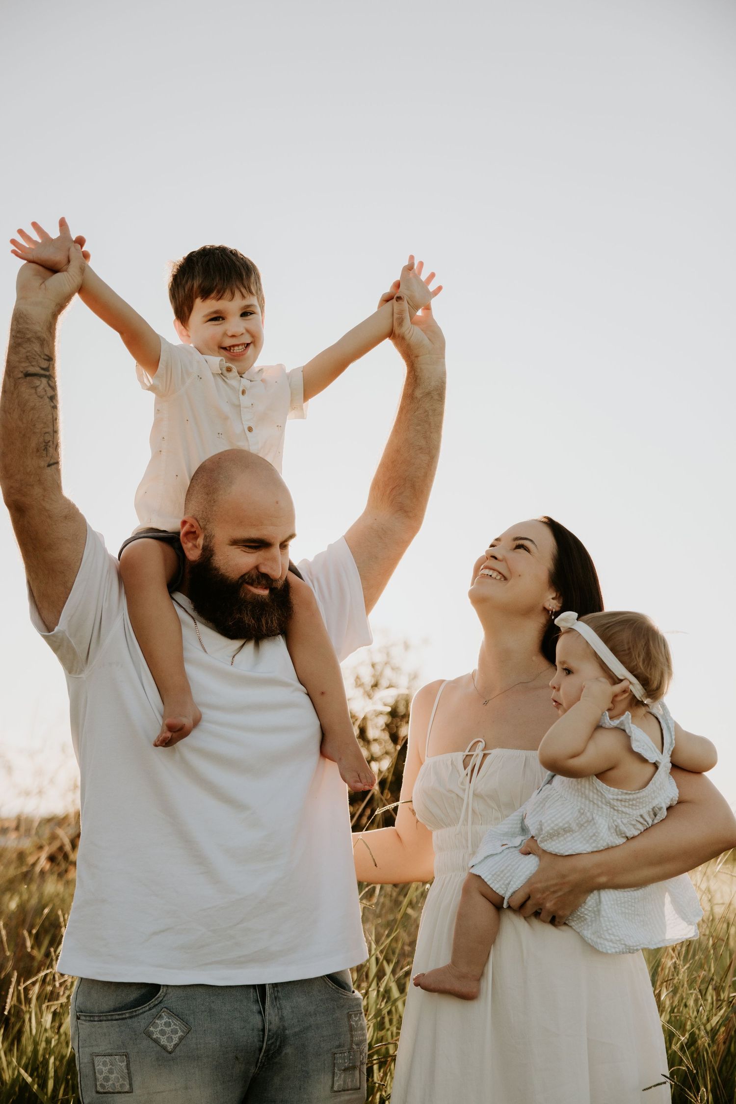Joyful family playing and laughing together in a grassy field at sunset.