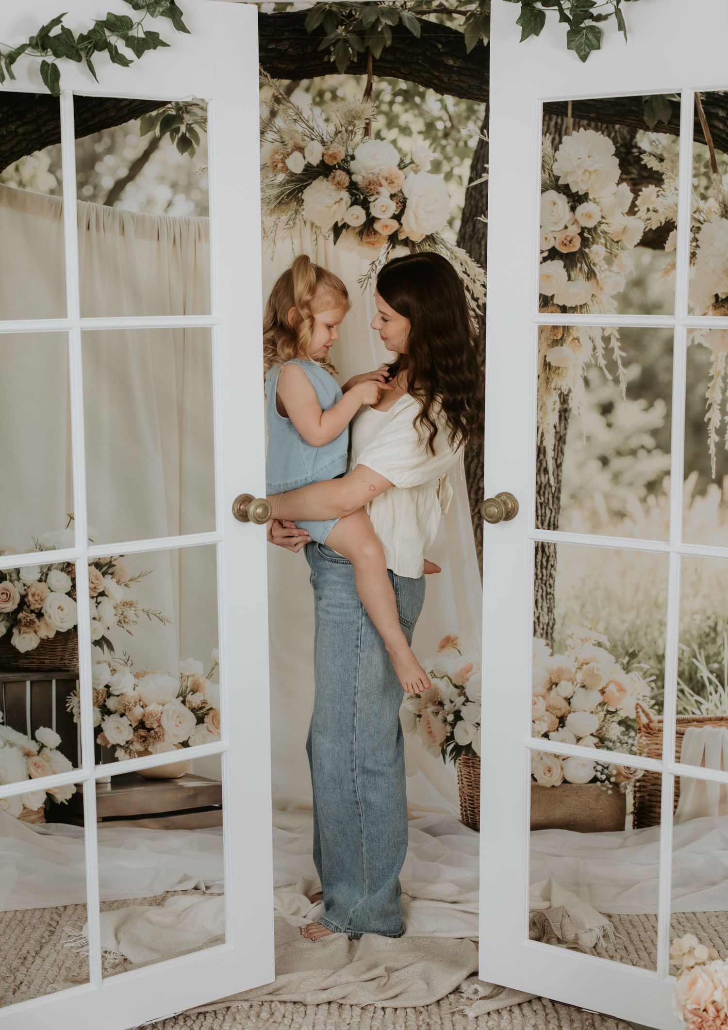 Intimate portrait against French doors with floral arrangements and natural lighting.