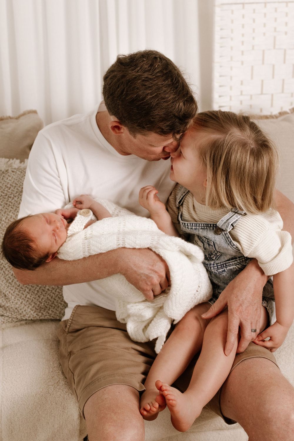 Candid family moments captured in black and white showing affection on couch.
