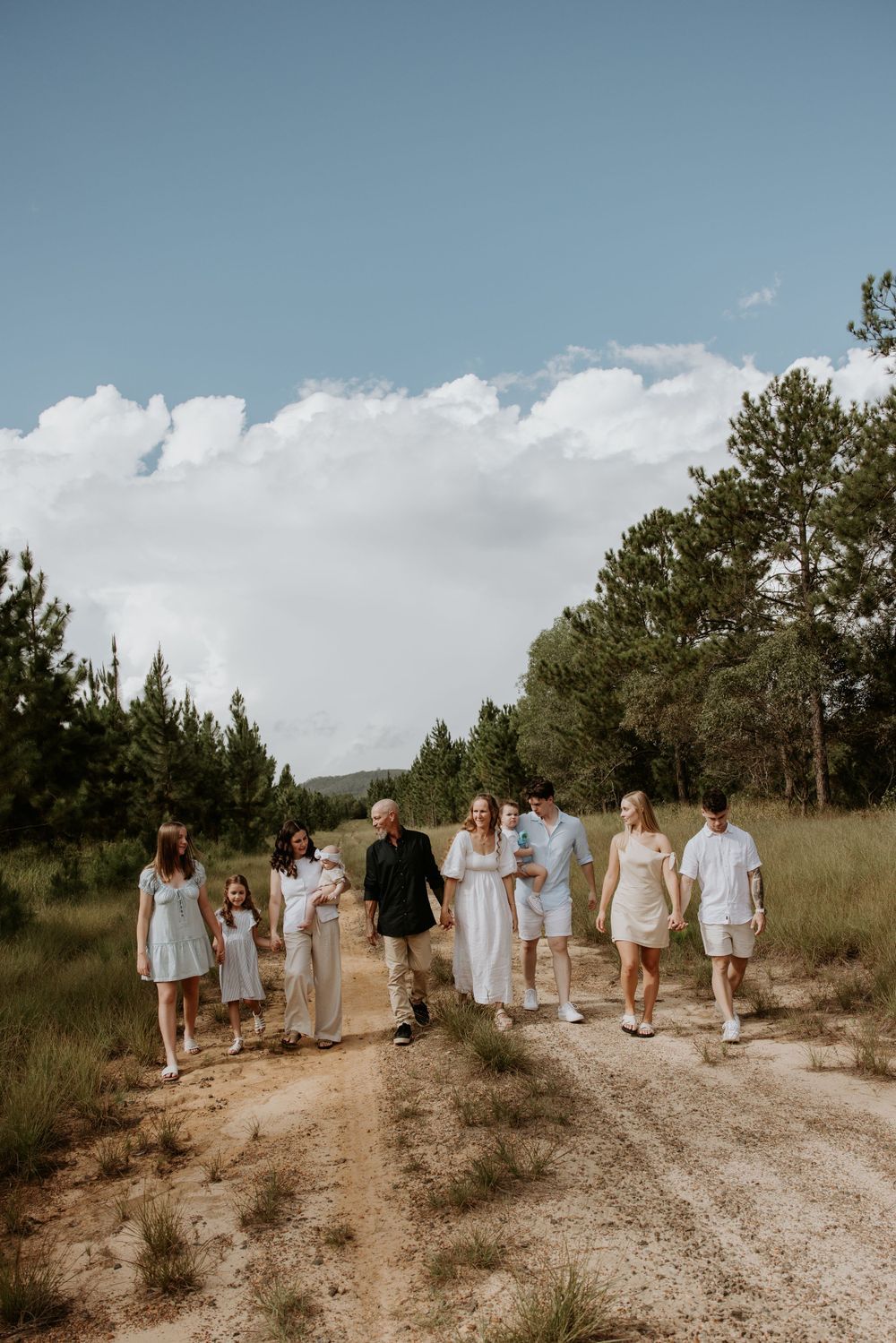 Group walks together on a dusty path through natural desert landscape under bright blue sky.