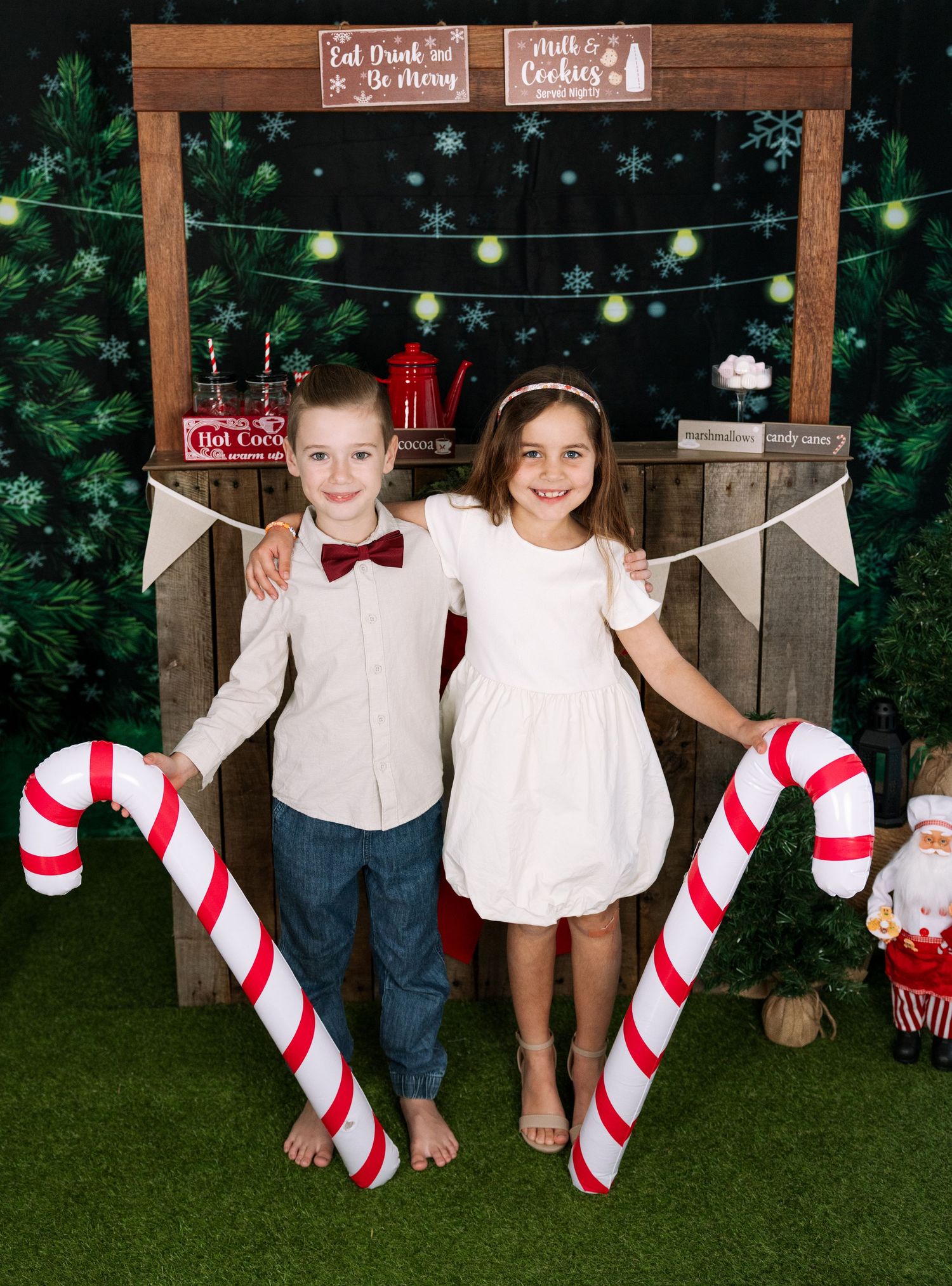 Children sit on wooden bench with candy cane props at holiday photo session.