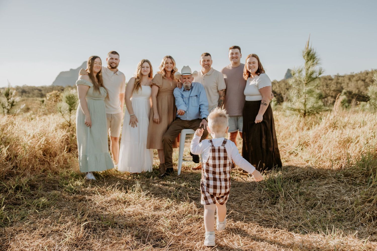 Group photo session in a natural outdoor setting with people arranged in casual poses on a hillside.
