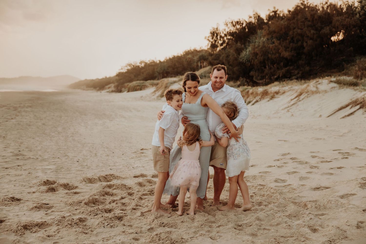 Family enjoying a sunset walk together on a sandy beach.