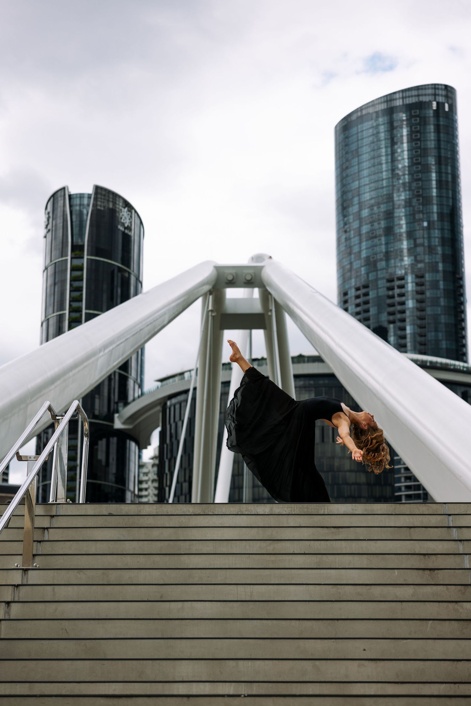 Dynamic dance poses on urban steps with modern buildings in background.