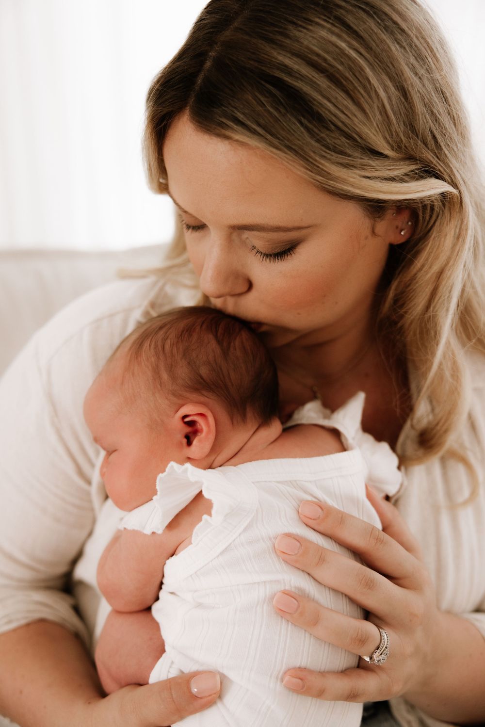 Tender moments between parent and newborn during indoor portrait session.