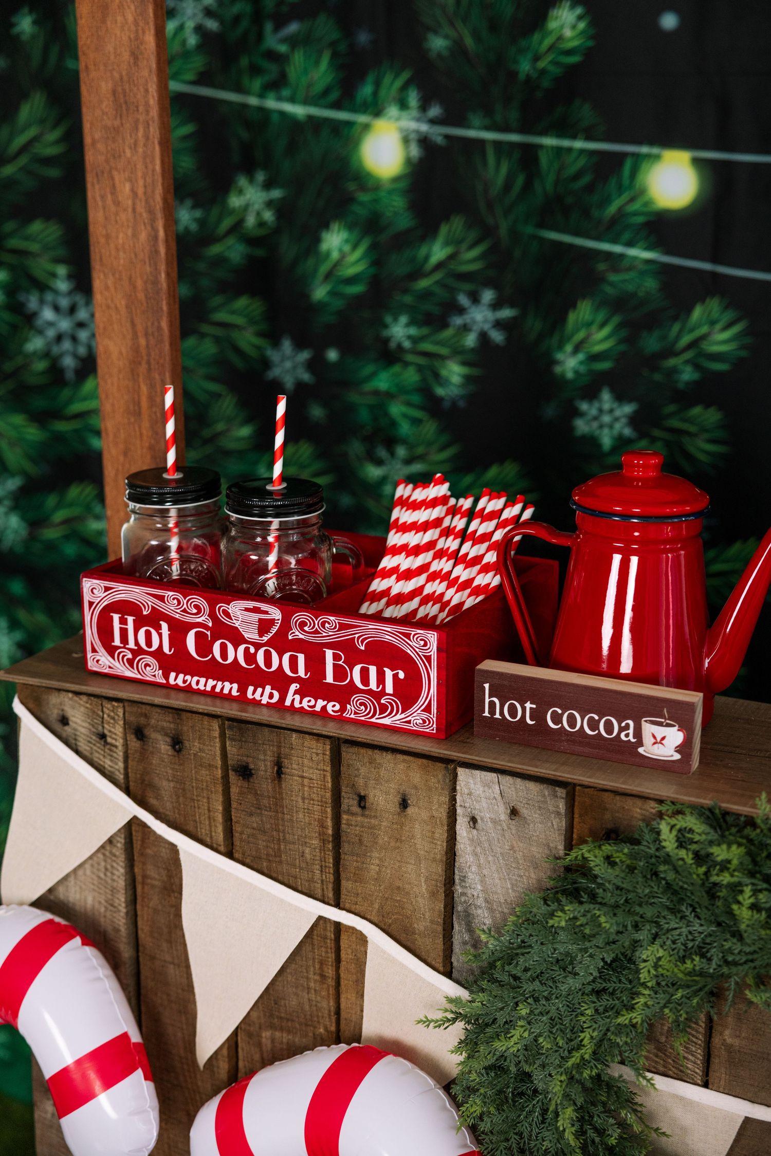 Rustic hot cocoa bar with candy canes and red teapot at Christmas event.