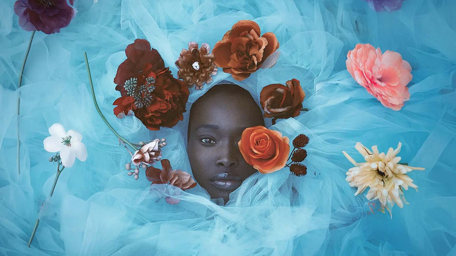 Artistic floral composition with roses and flowers on bright blue background.