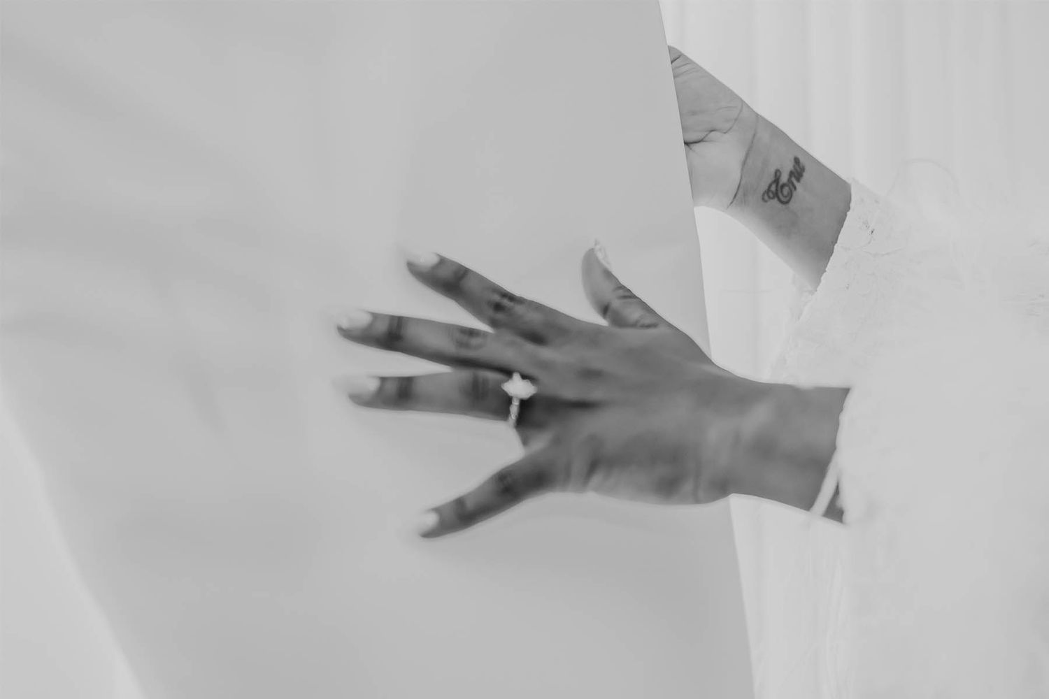 A black and white close-up of a hand with an engagement ring.