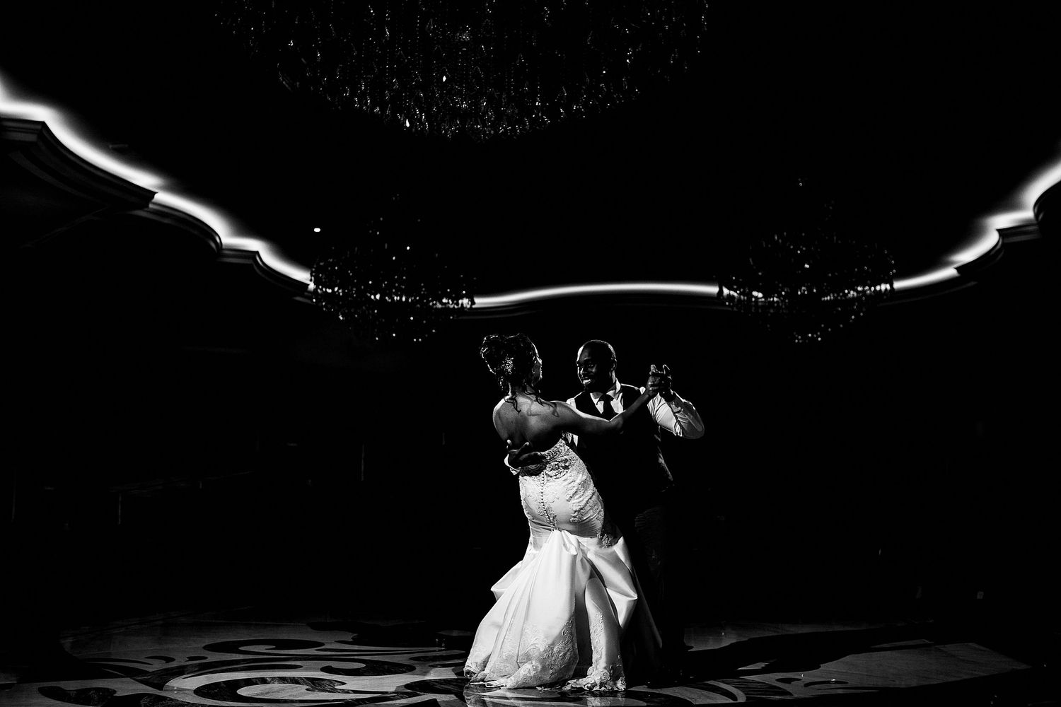 Black and white underwater wedding photo with dramatic lighting effects.