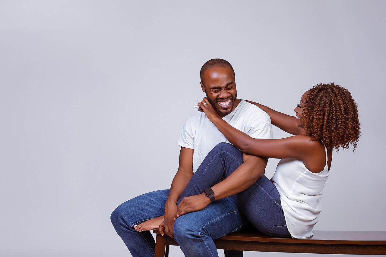 A casual portrait showing a playful interaction on a bench against white background.