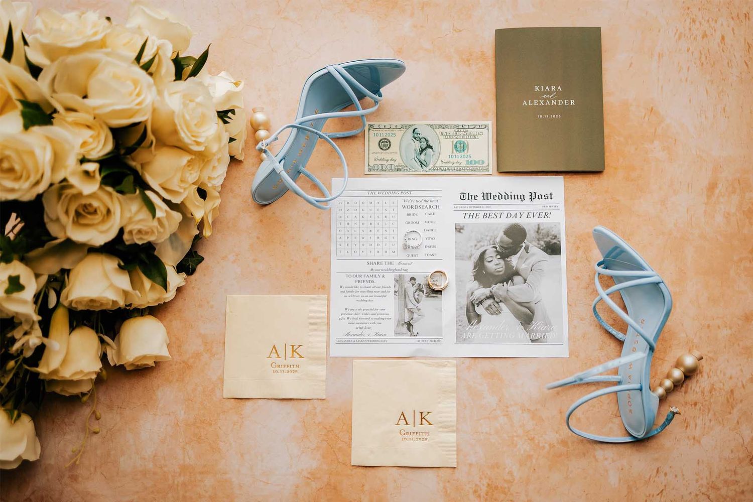 Wedding invitation suite with white roses and blue accents on a peach-colored background.