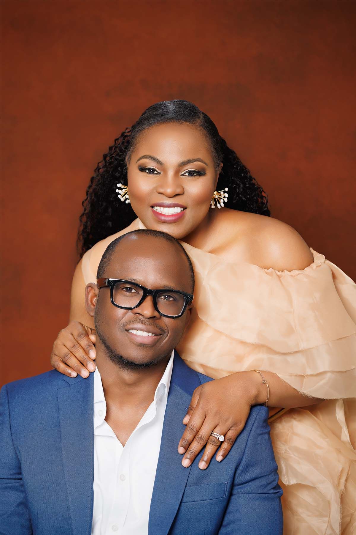 Intimate portrait against red background with coordinated peach and navy formal attire.