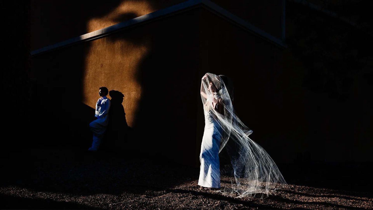 Creative nighttime wedding photo with couple silhouetted against dramatic lighting.
