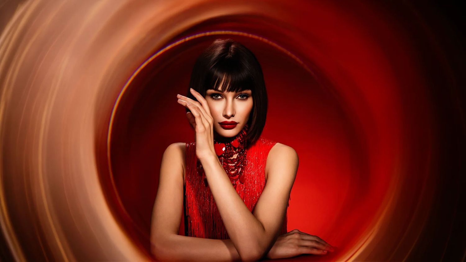 Dramatic fashion portraits set against a deep red spiral background.