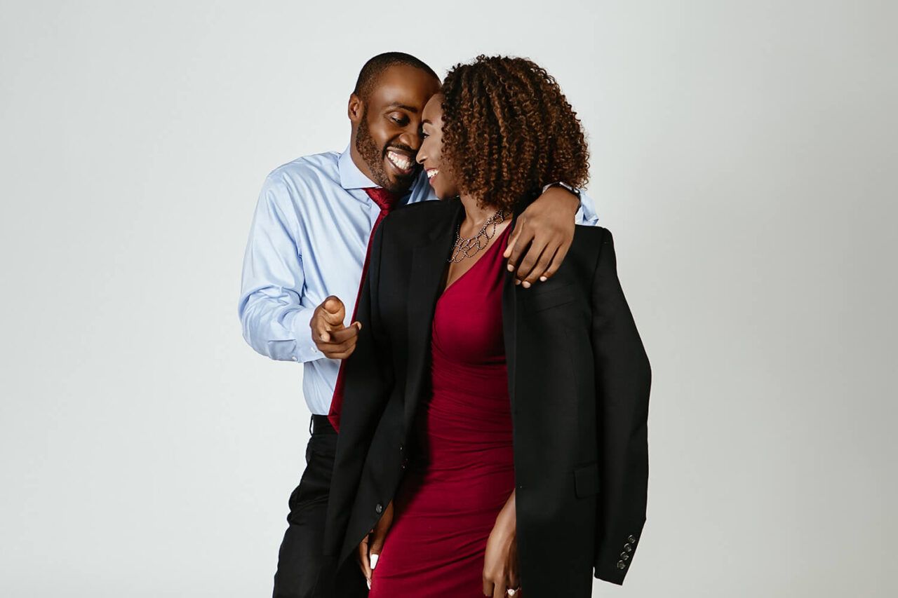 An intimate couple embracing in formal attire against a white studio backdrop.