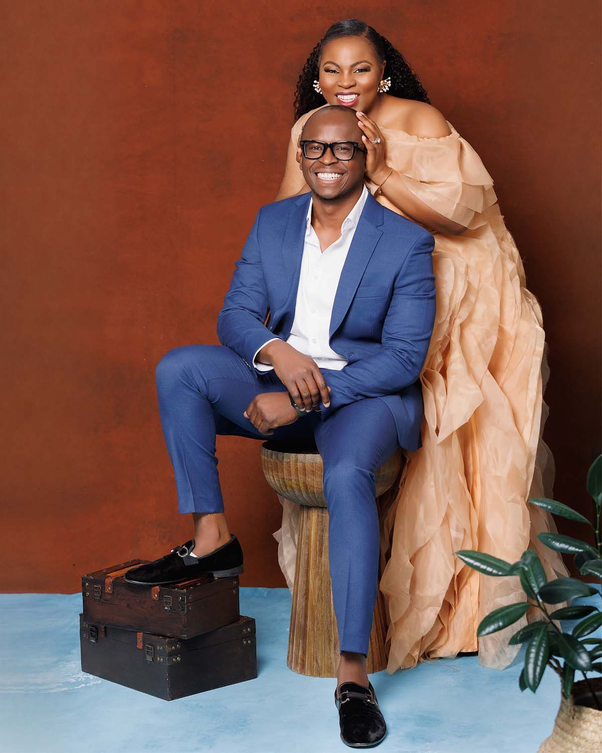 Stylish family photo session with coordinated outfits against terracotta wall.