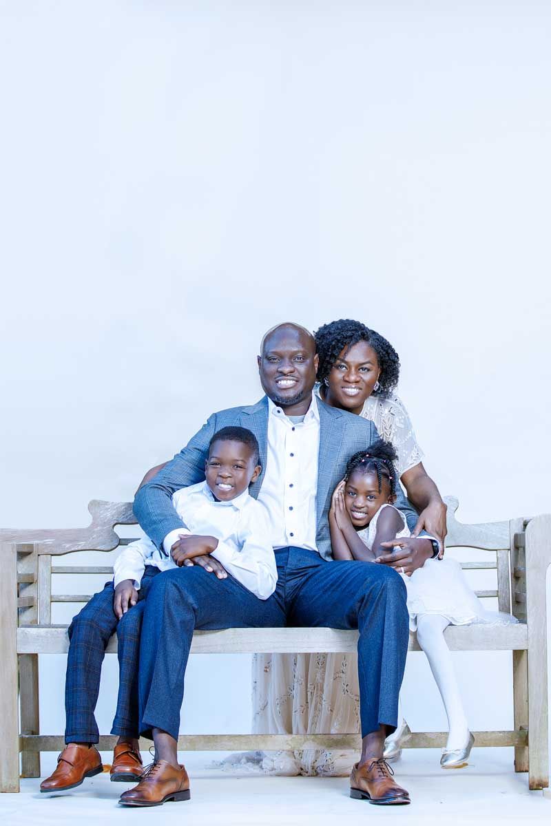 A family sits together on wooden benches wearing coordinated blue and white outfits.