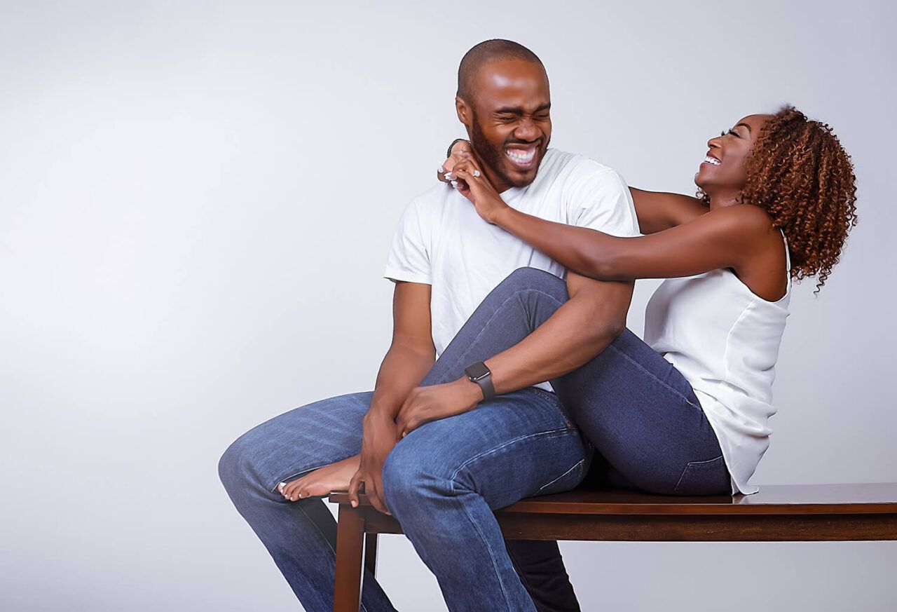 Couple in casual attire sharing intimate moments in artistic black and white studio photoshoot.
