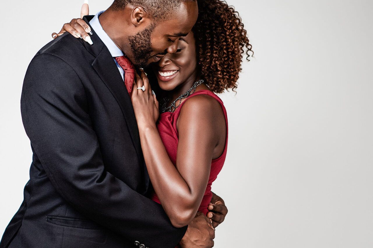 An intimate moment captured between a couple in formal wear against white background.