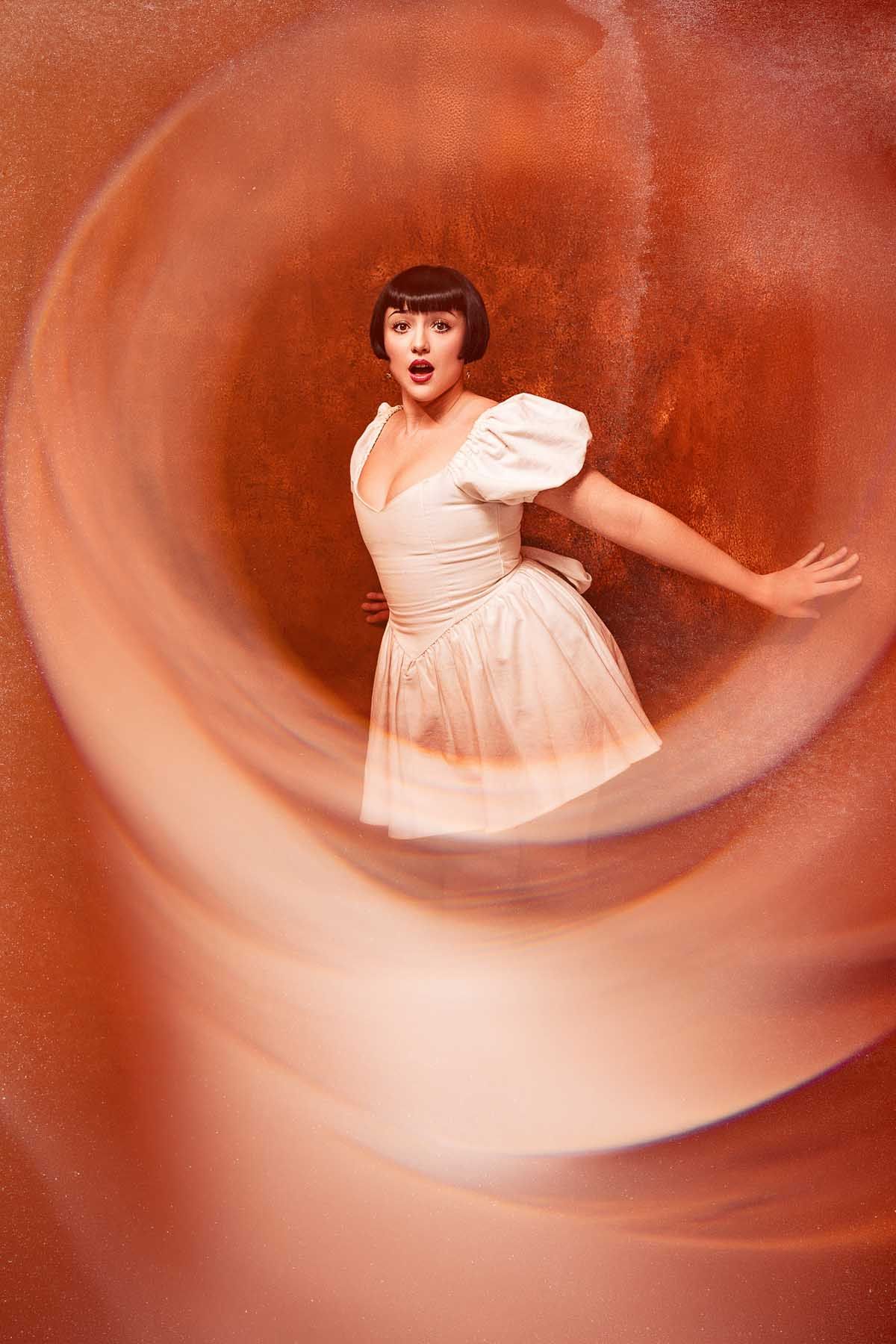 Dynamic spinning sequence of a white dress against an orange background.