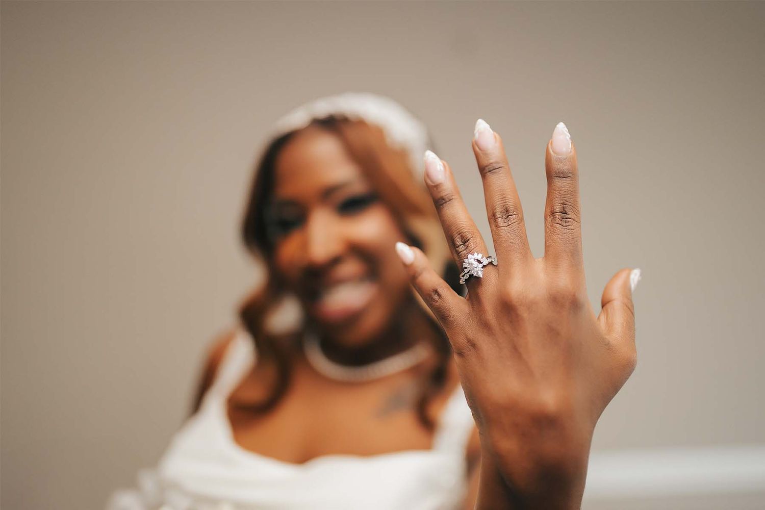 Close-up shot of hands showing off wedding rings against a neutral background.