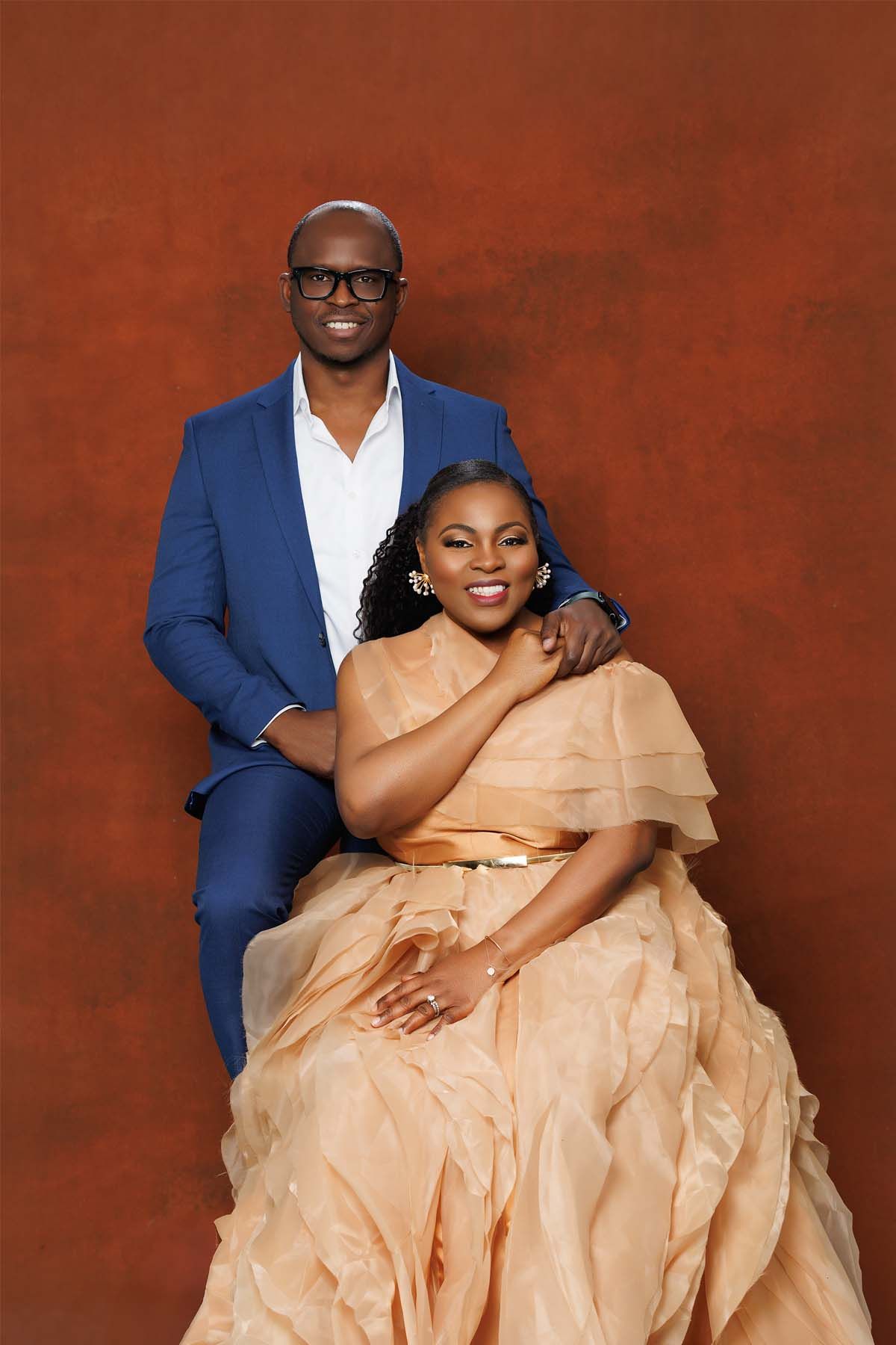 Couple poses formally together with man in blue suit and woman in peach gown.