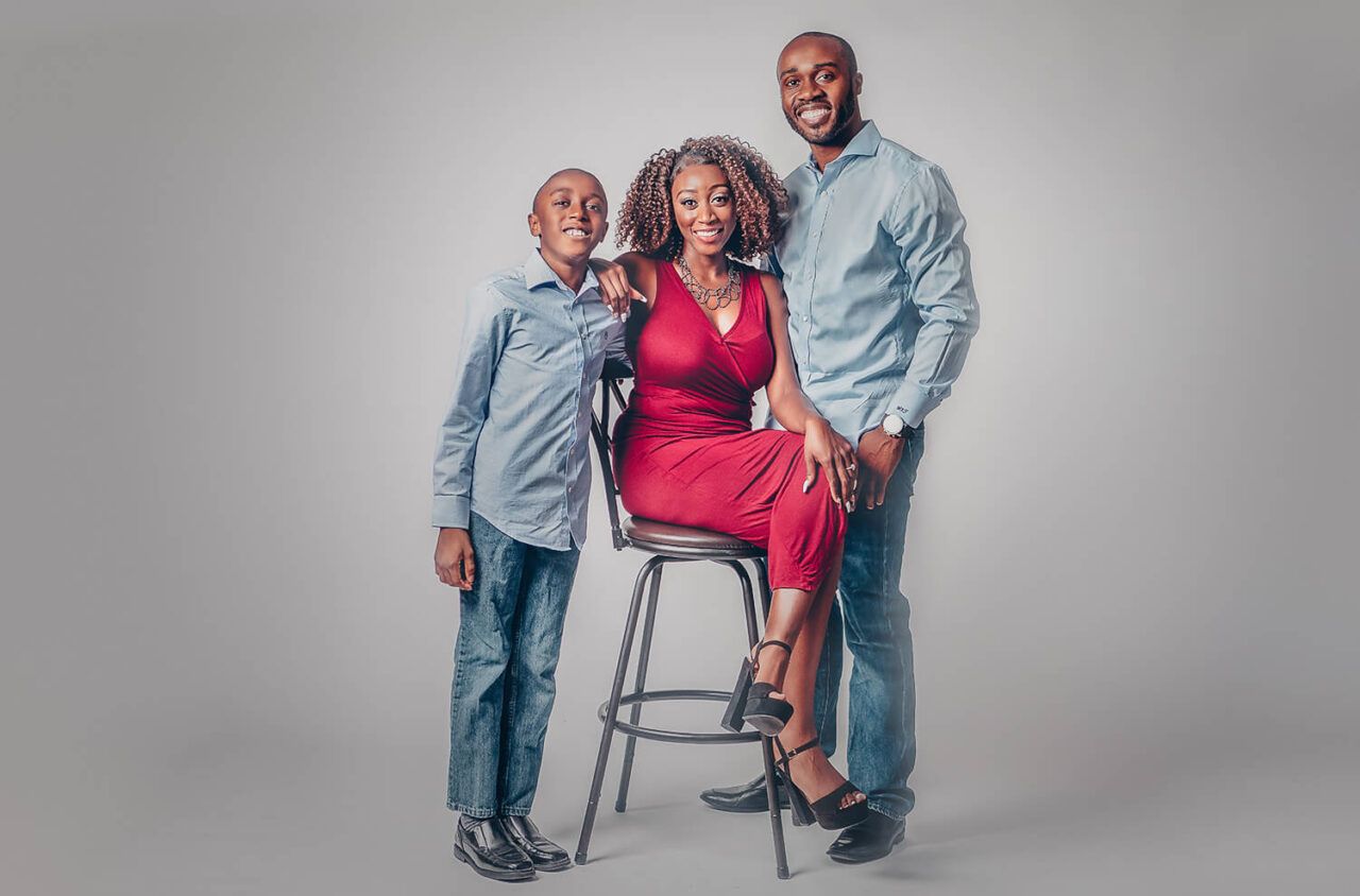 A family portrait against a gray background featuring casual and formal attire.