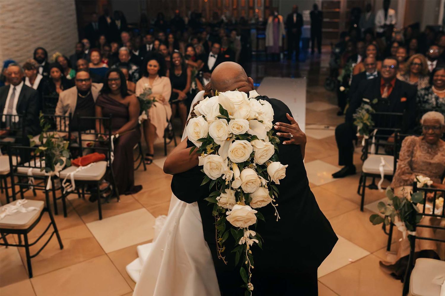 Wedding ceremony setup with white floral arrangements and guest seating in an elegant venue.