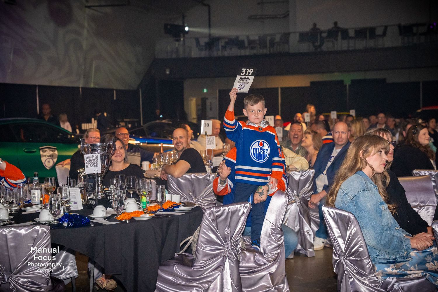 A Kid holding up his table number for a auction