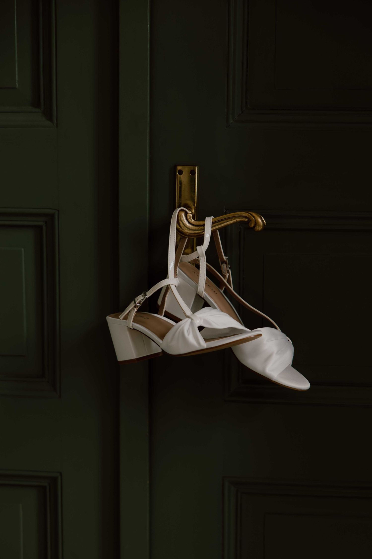 trouwschoenen hangen aan deur van de trouwlocatie
