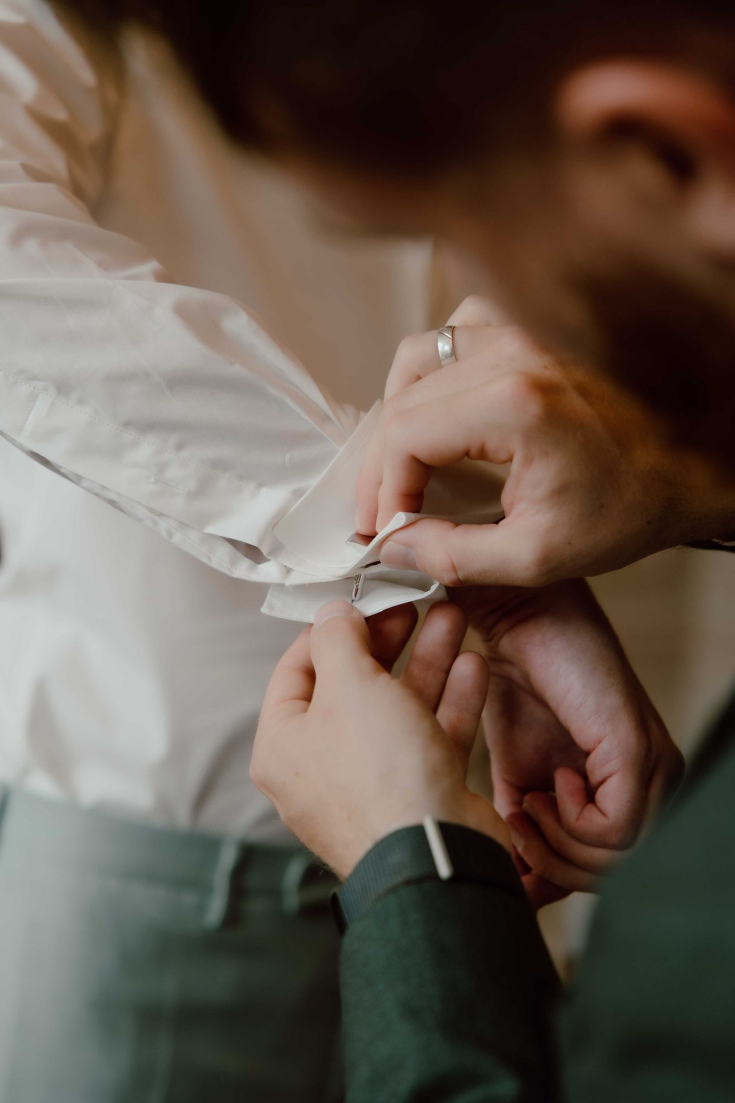 vriend helpt bruidegom met knoopjes blouse vastmaken