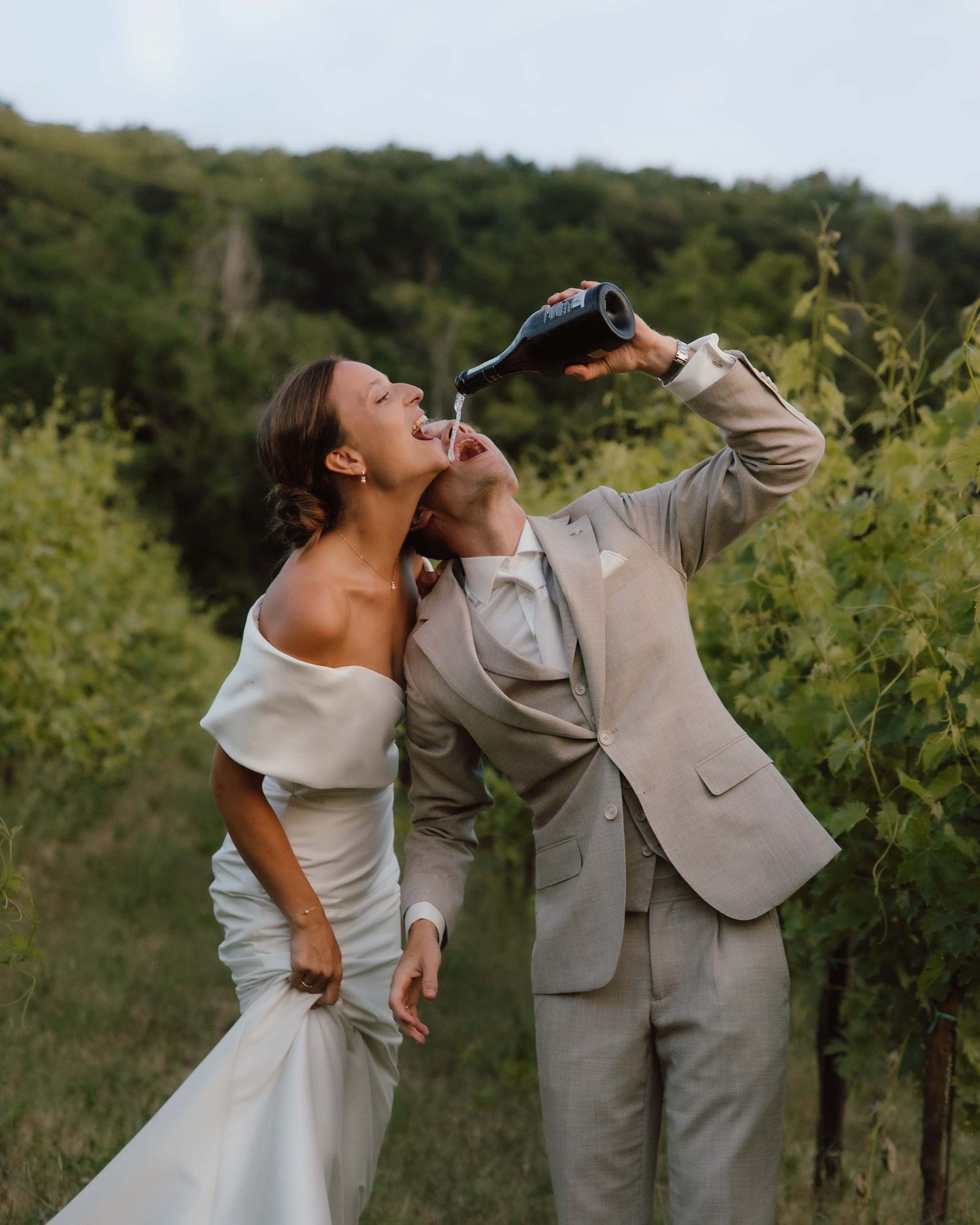 Bruidspaar drink van champagne fles in de wijnvelden in het zonnige Italië