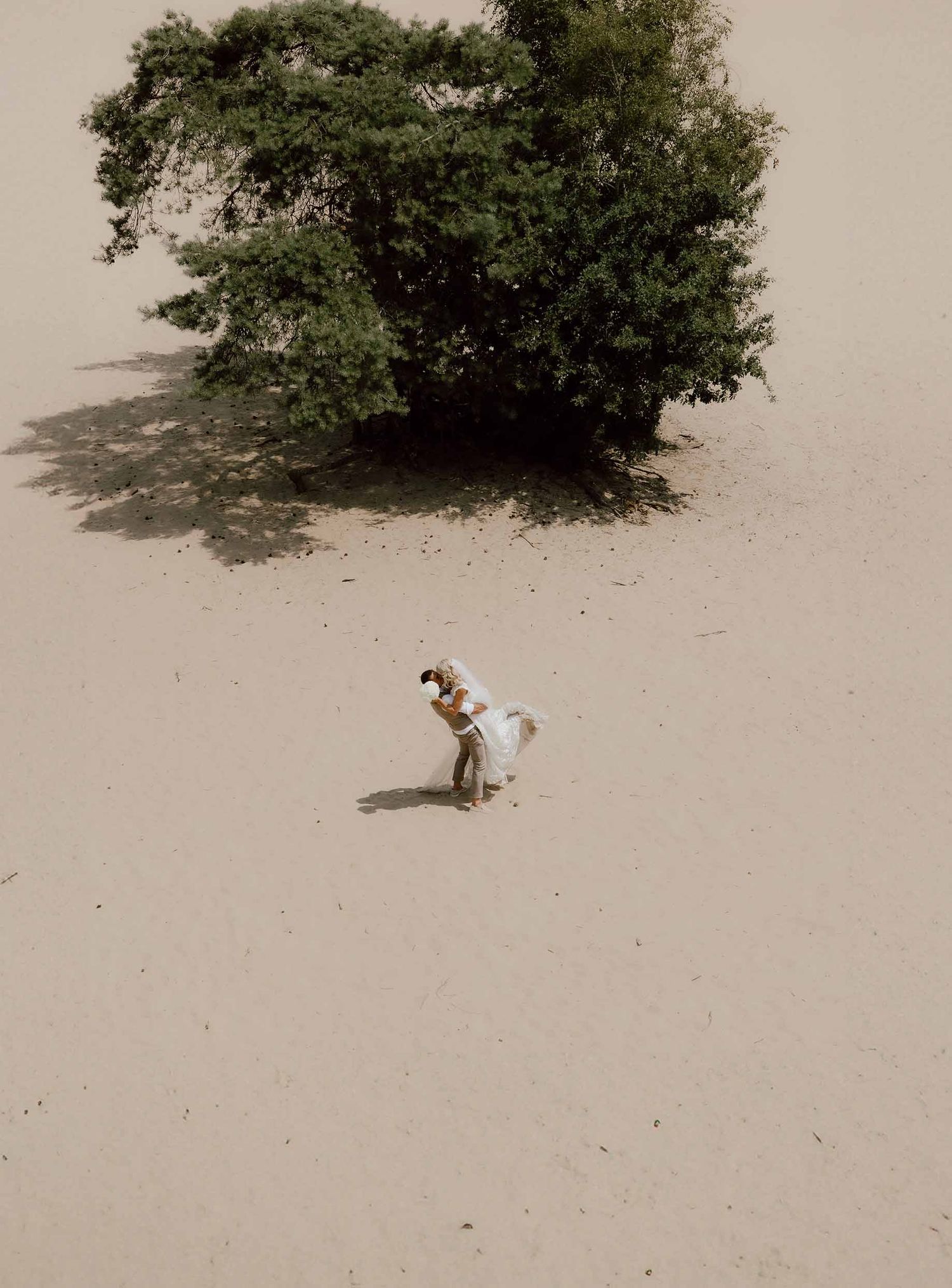 Drone foto tijdens loveshoot op zandvlakte met bruidspaar