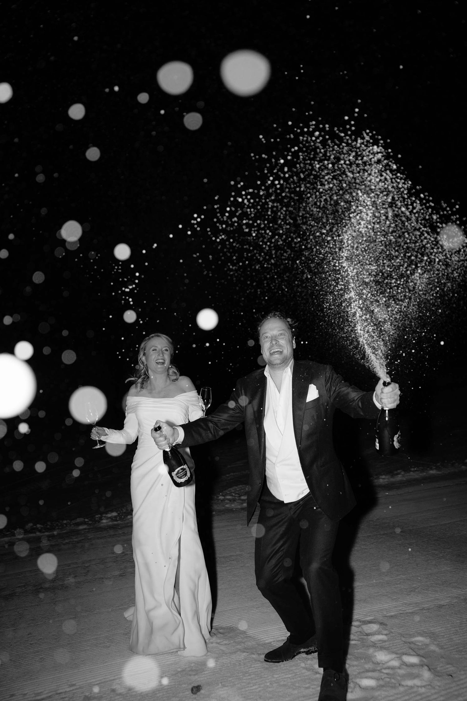Bruidspaar in Flachau, Oostenrijk die een fles champagne poppen