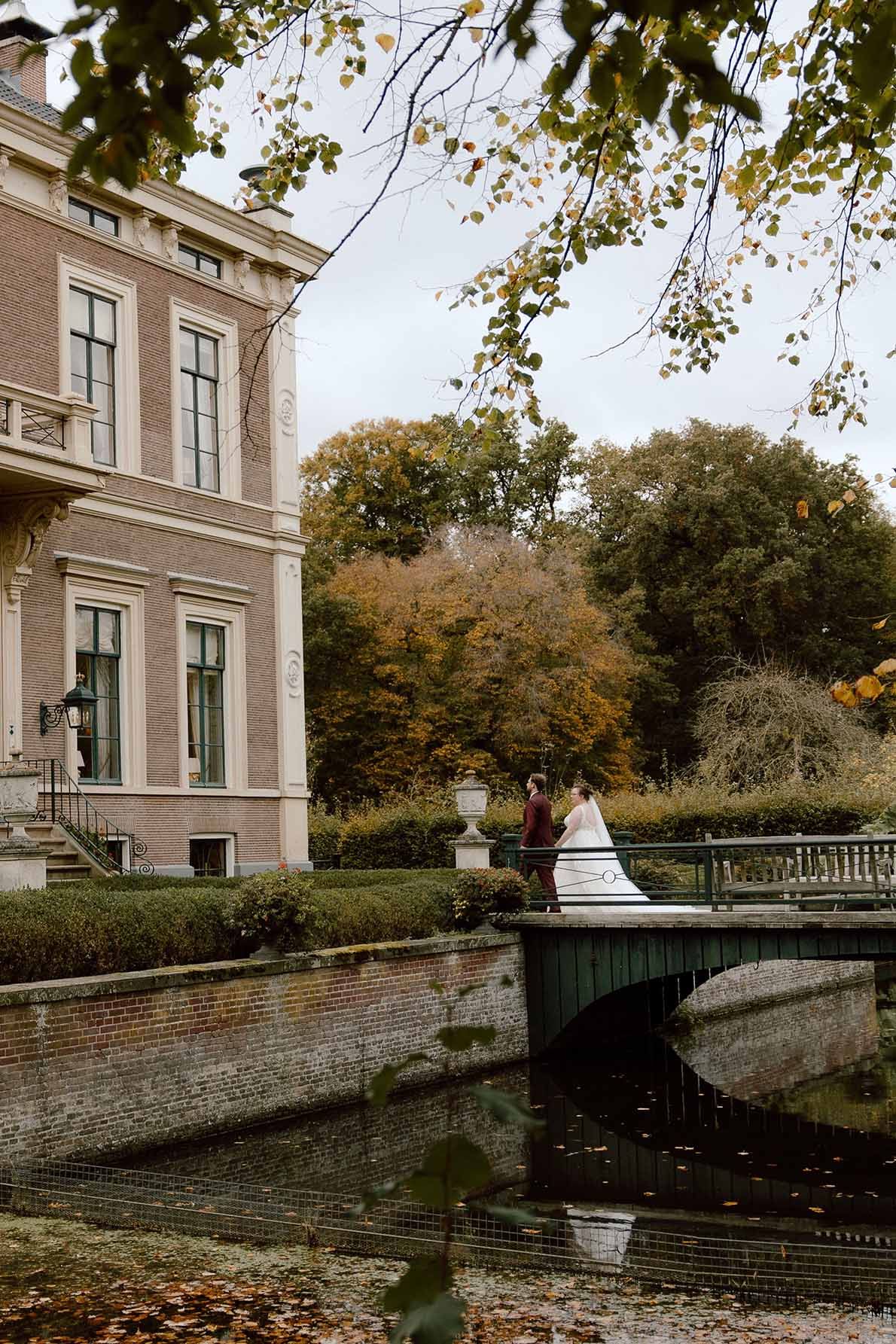 Bruidspaar loopt voor de bruiloft samen het kasteel in op een herfst dag