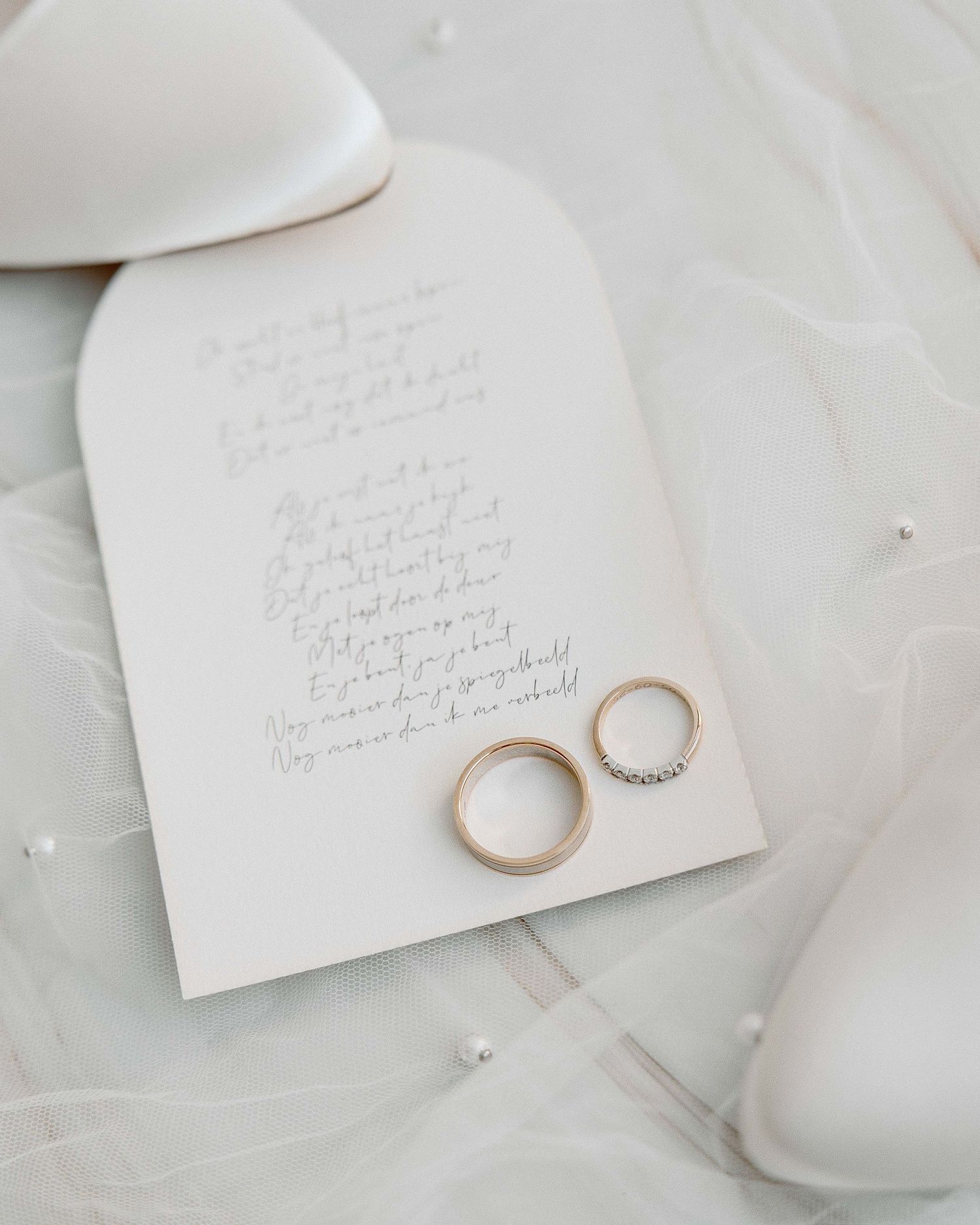 trouwringen liggen op de trouwkaart tijdens het klaarmaken en de detail en flatlay foto's