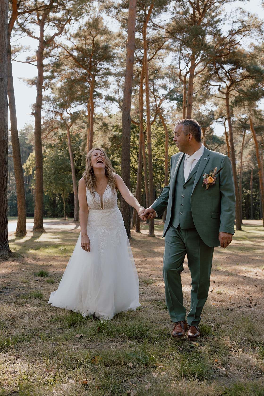 Bruidspaar tijden de loveshoot in het bos in de herfst op hun trouwdag