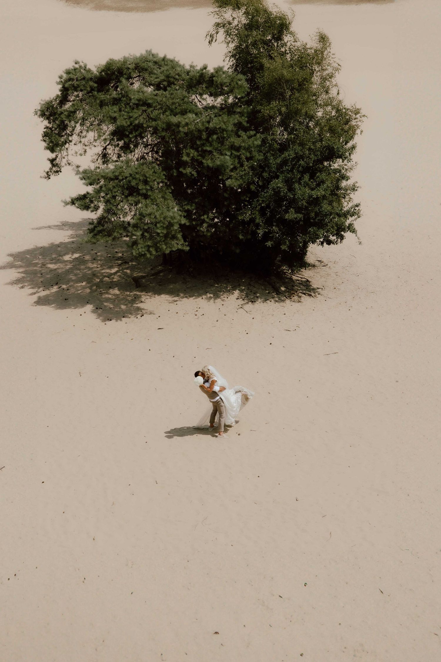 Bruidspaar op zandvlakte drone shot - spontane trouwfotografie in Almere, Flevoland.