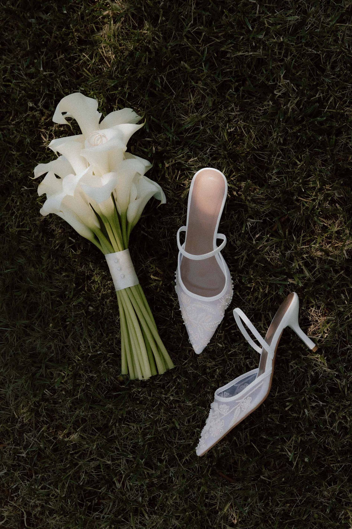 Witte trouwschoenen met trouwboeket op het grasveld