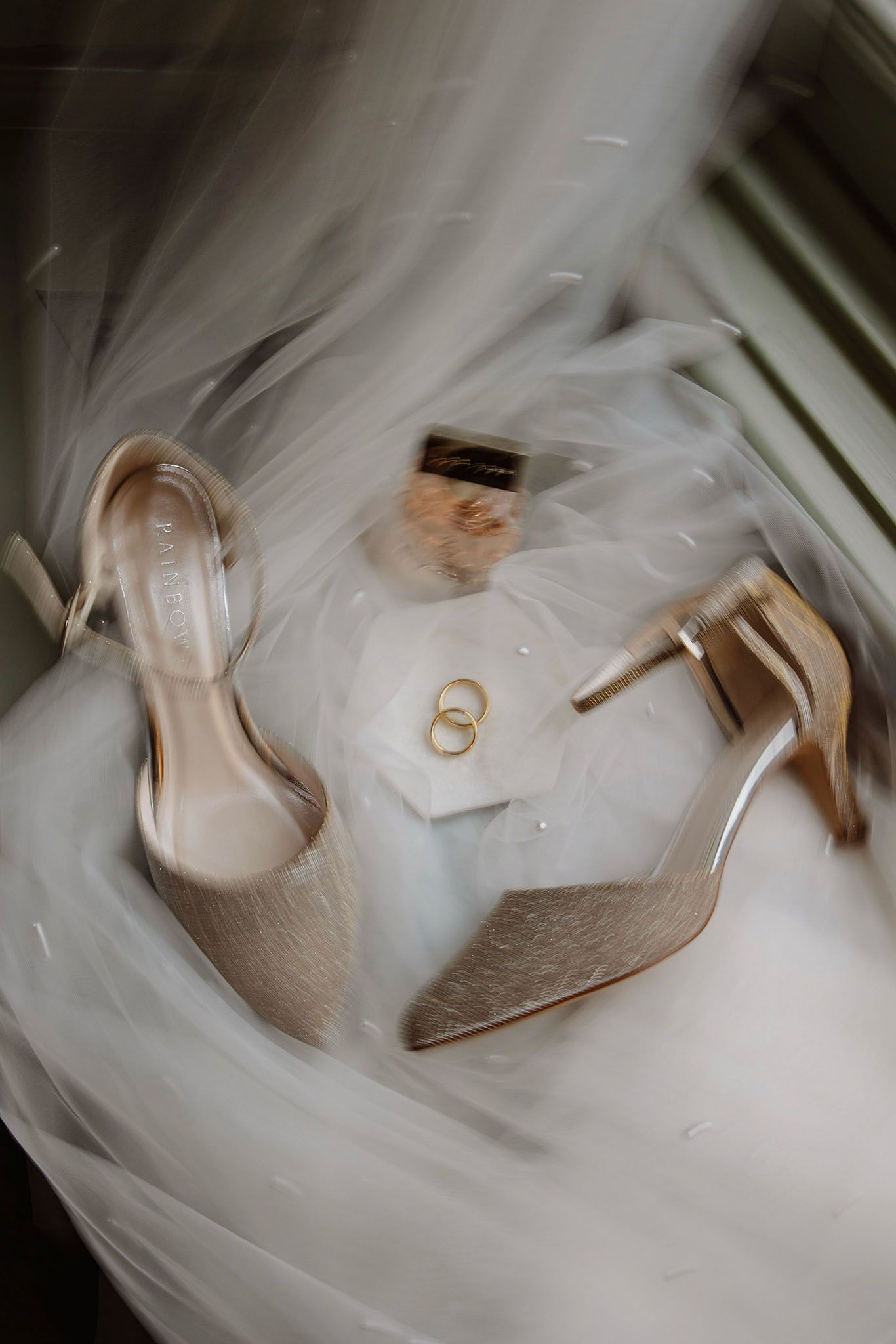 Detail foto van ringen trouwschoenen en sluier