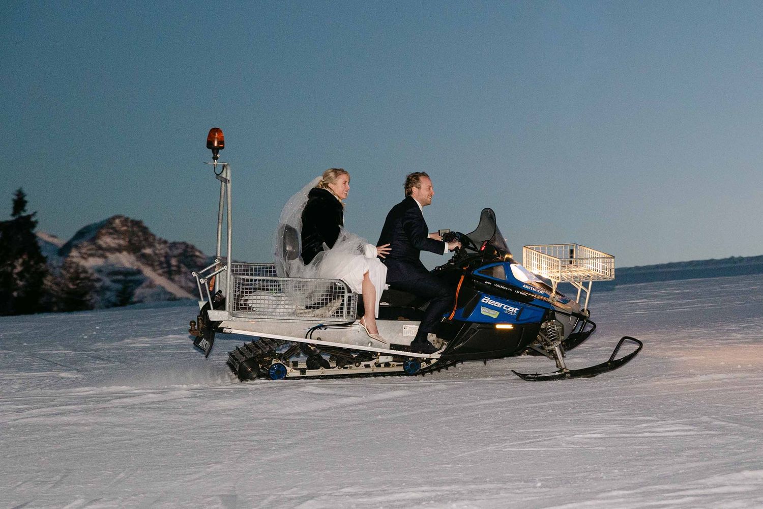 Bruidspaar op een sneeuwscooter in Flachau, Oostenrijk tijdens een winterbruiloft