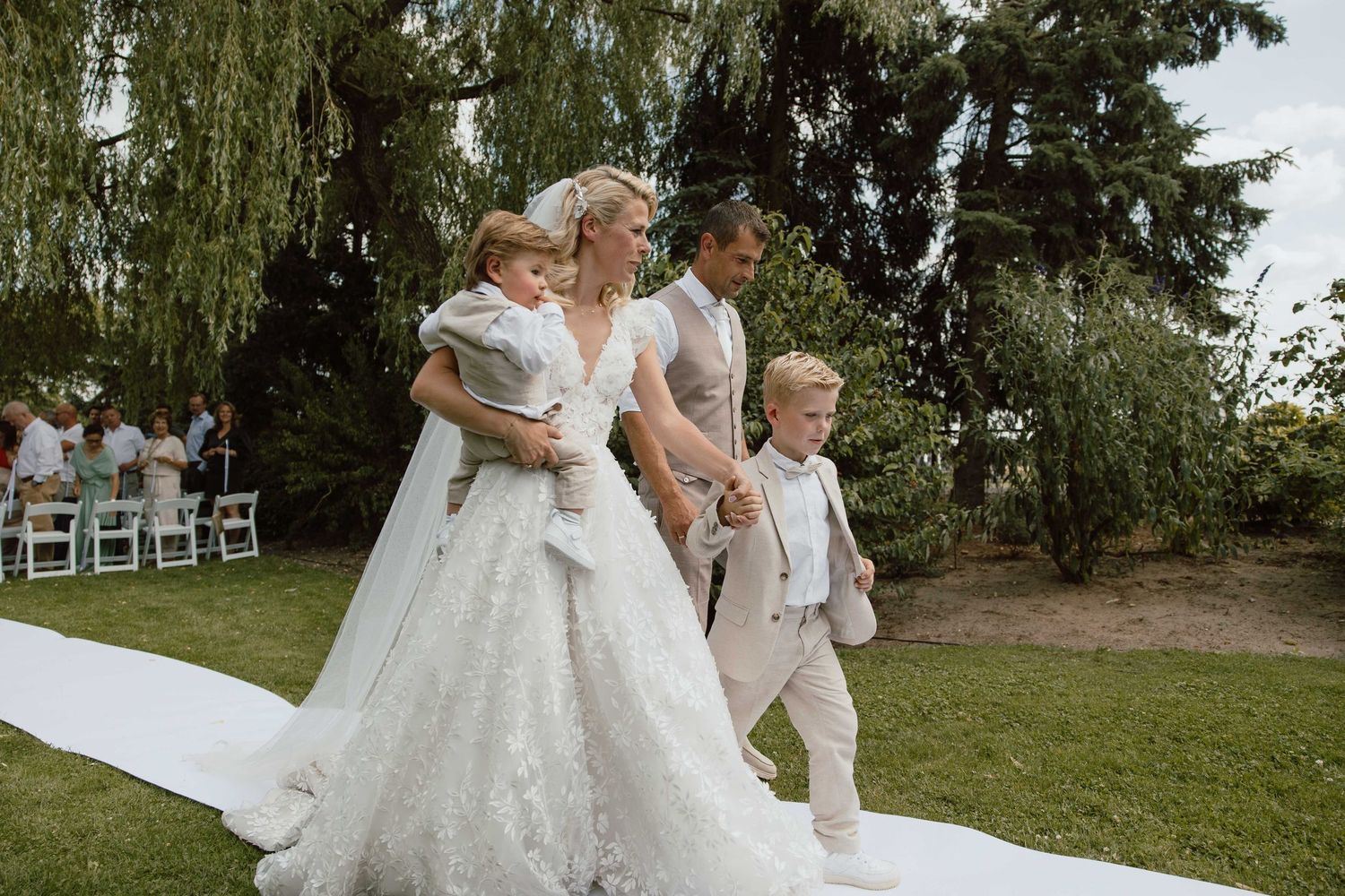 Bruidspaar loopt samen met kinderen weg na de ceremonie - spontane trouwfotografie in Almere, Flevoland.