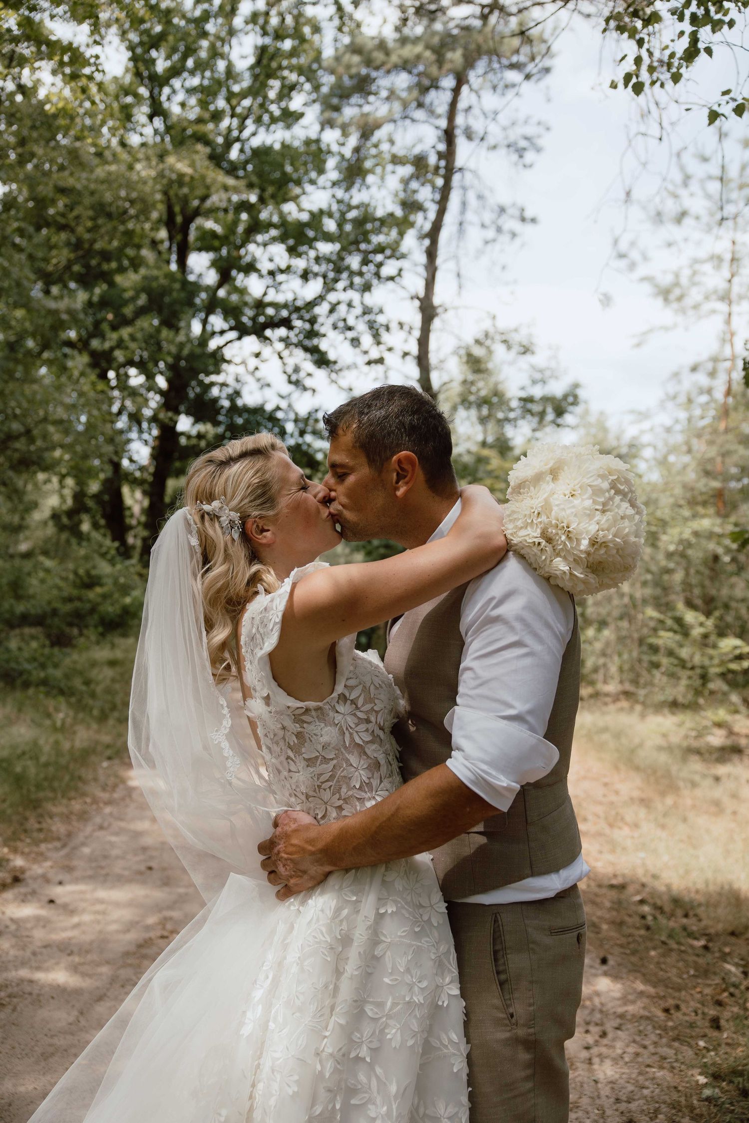 Bruidspaar geeft elkaar een kus tijdens loveshoot in het bos - spontane trouwfotografie in Almere, Flevoland.