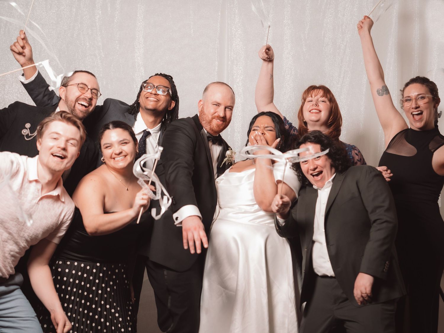 Bride and groom celebrate with large group of friends holding sparklers at wedding reception.
