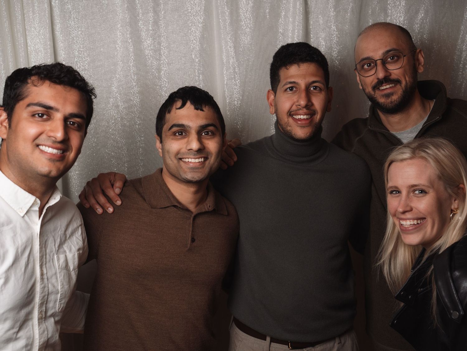 Five friends smile together in a group photo at a wedding reception event.
