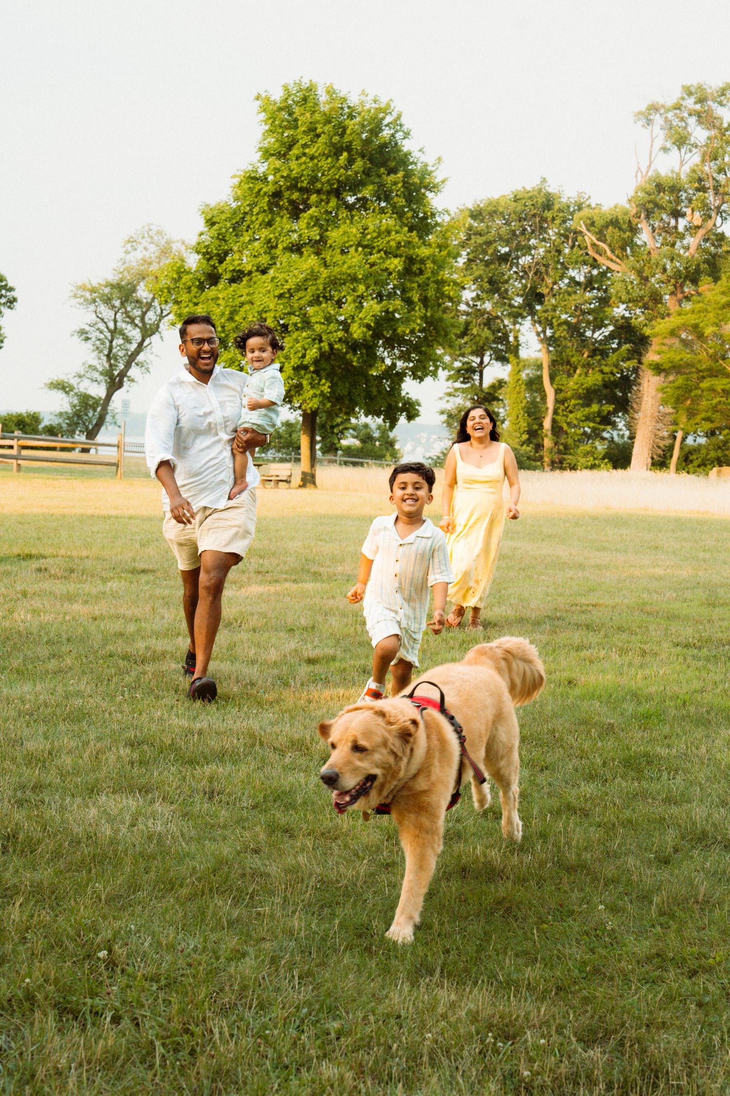 Happy family with a Golden Retriever running in a green park on a sunny day.